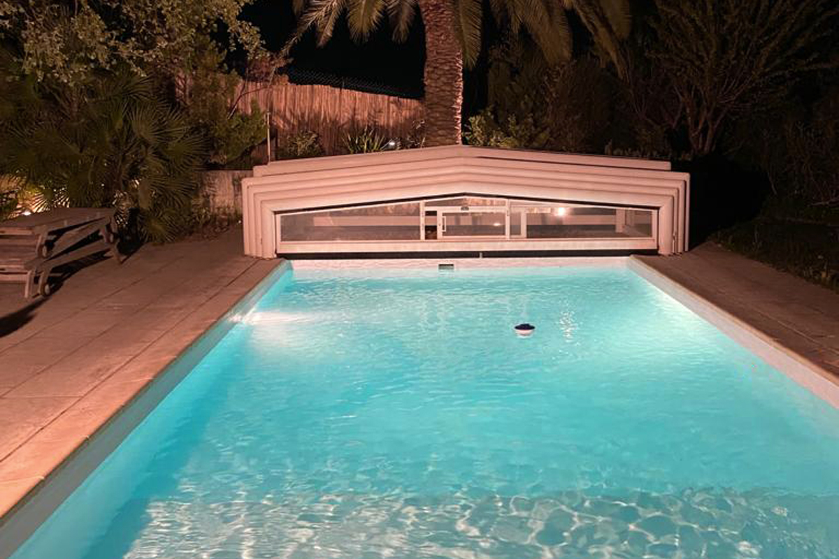 Aufnahme eines Beleuchteten Pools mit zurückgefahrener Überdachung bei Nacht