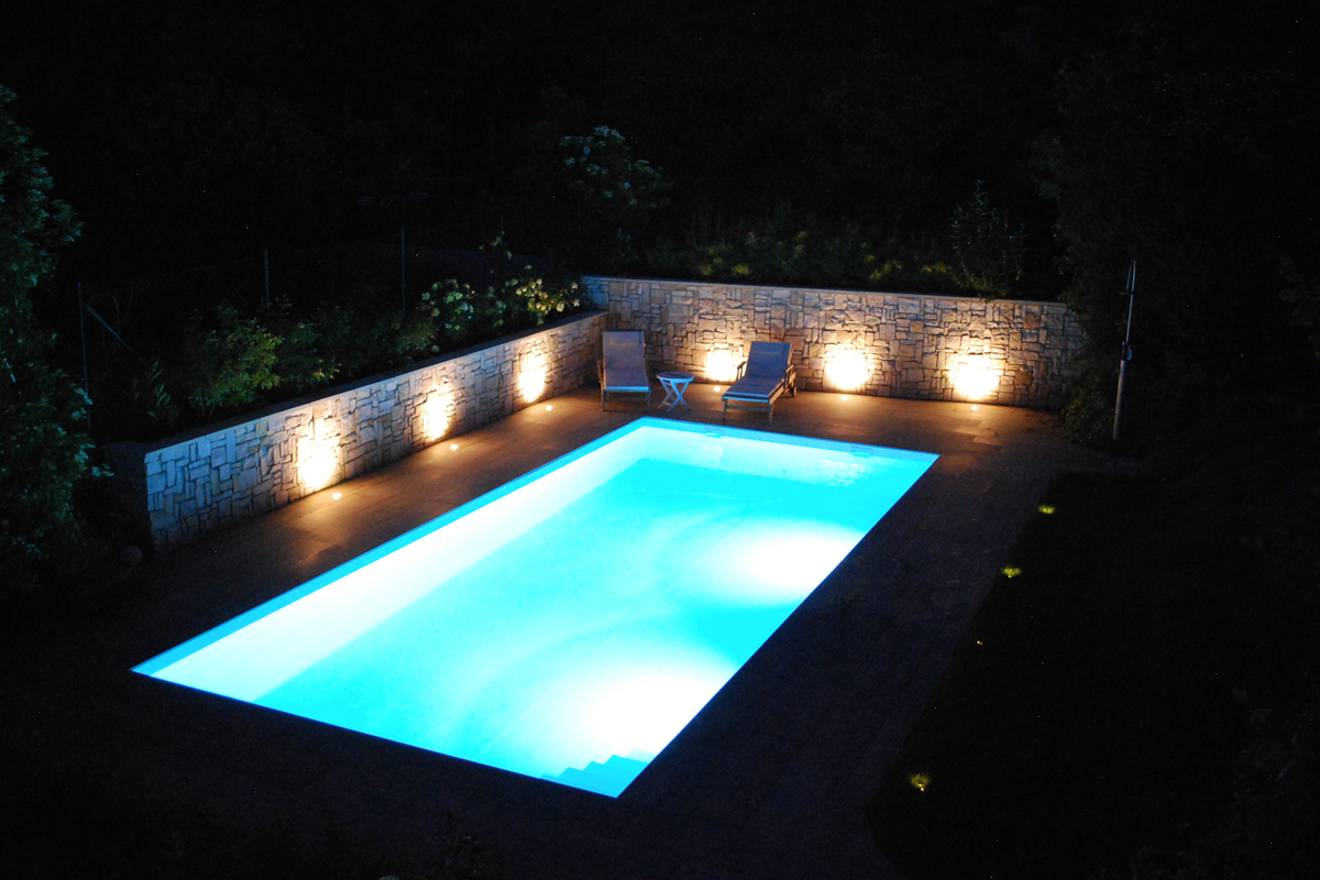Beleuchteter Pool in einem Garten bei Nacht
